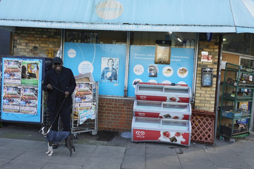 Edward Enninful smiles with his dog, Ru, outside a newsagents in London