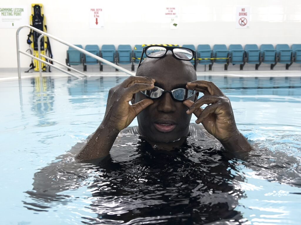 Edward Enninful pictured in a swimming pool with glasses on his head and goggles over his eyes
