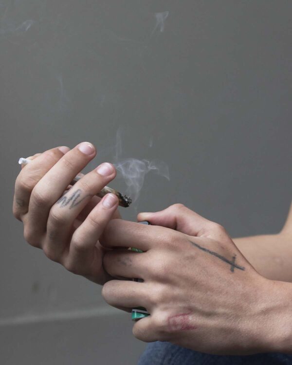 Close-up of tattooed hands lighting a joint