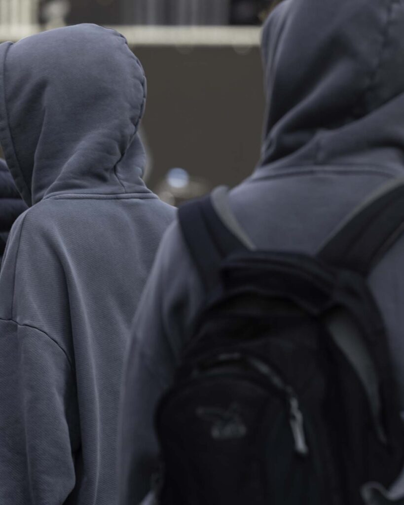 Oblique shot of grey hoodies facing away from the camera, wearing hoodies