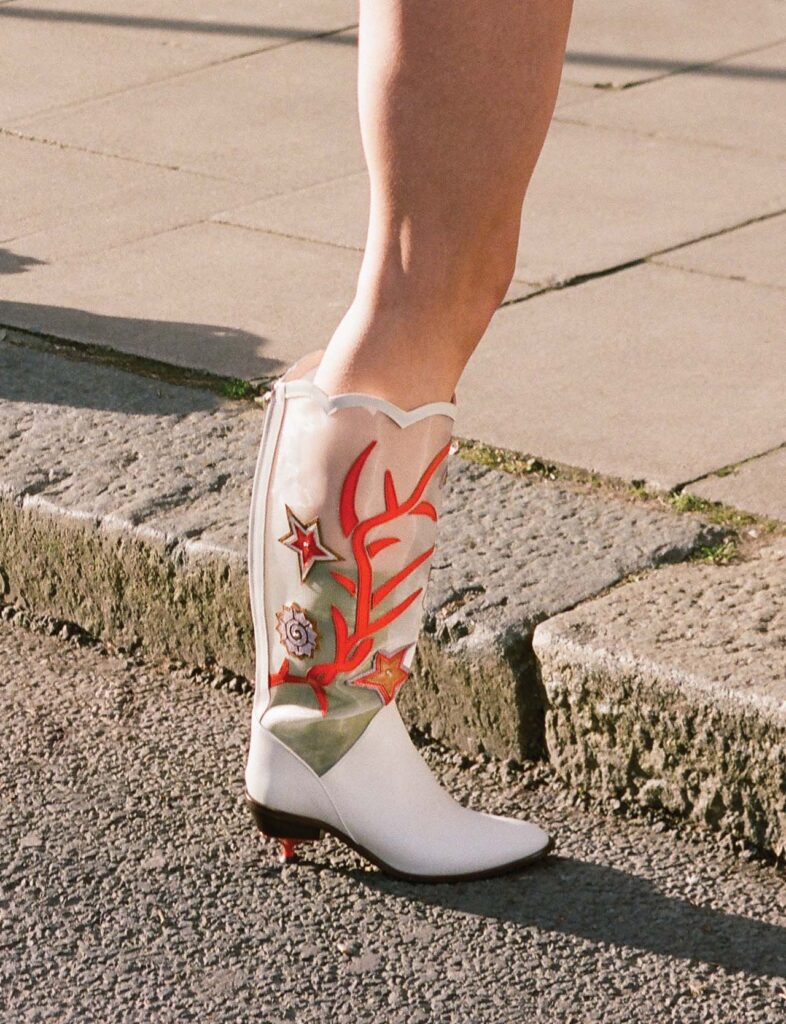 Close-up of white heeled boot on pavement with coral and starfish detailing