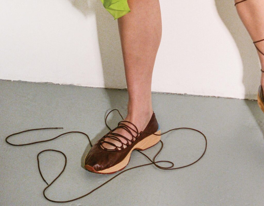 Close-up of brown laced ballet sneaker with laces splayed on the floor