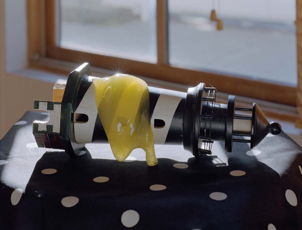 Model lighthouse lies on its side atop a polkadot surface, with a dollop of yellow slime dripping down it