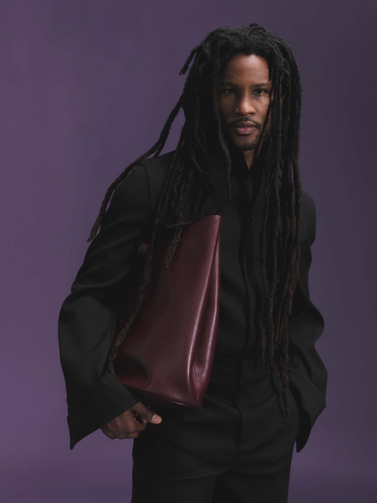 Akinola wears Bottega tailoring and carries a burgundy leather bag