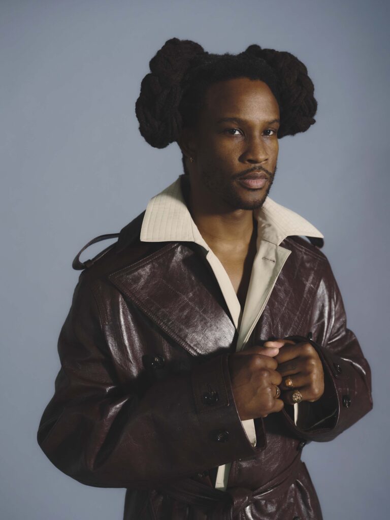 Intimate shot of Akinola in double Bottega trench coat with bunched hair