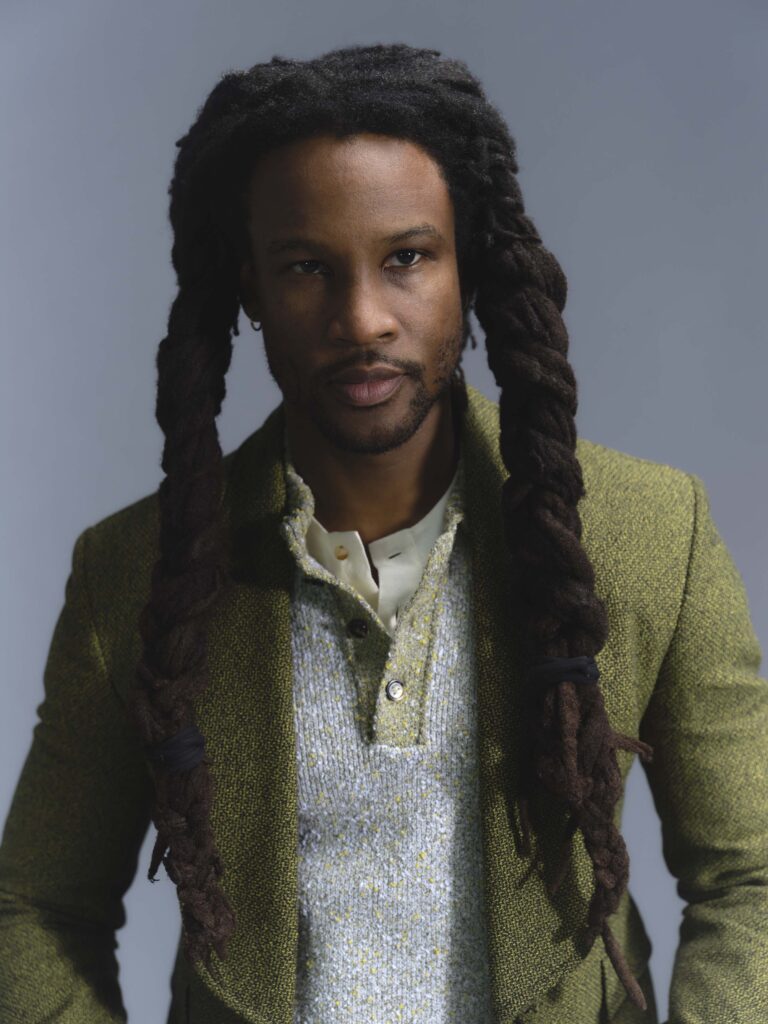 Akinola with hair styled in thick dreadlocks and wearing Bottega tweed-effect wool look