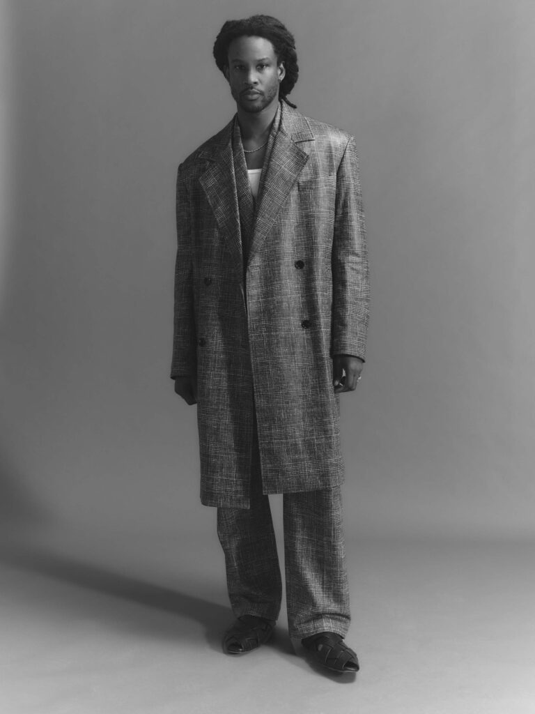 Full-length black and white shot of Akinola in long