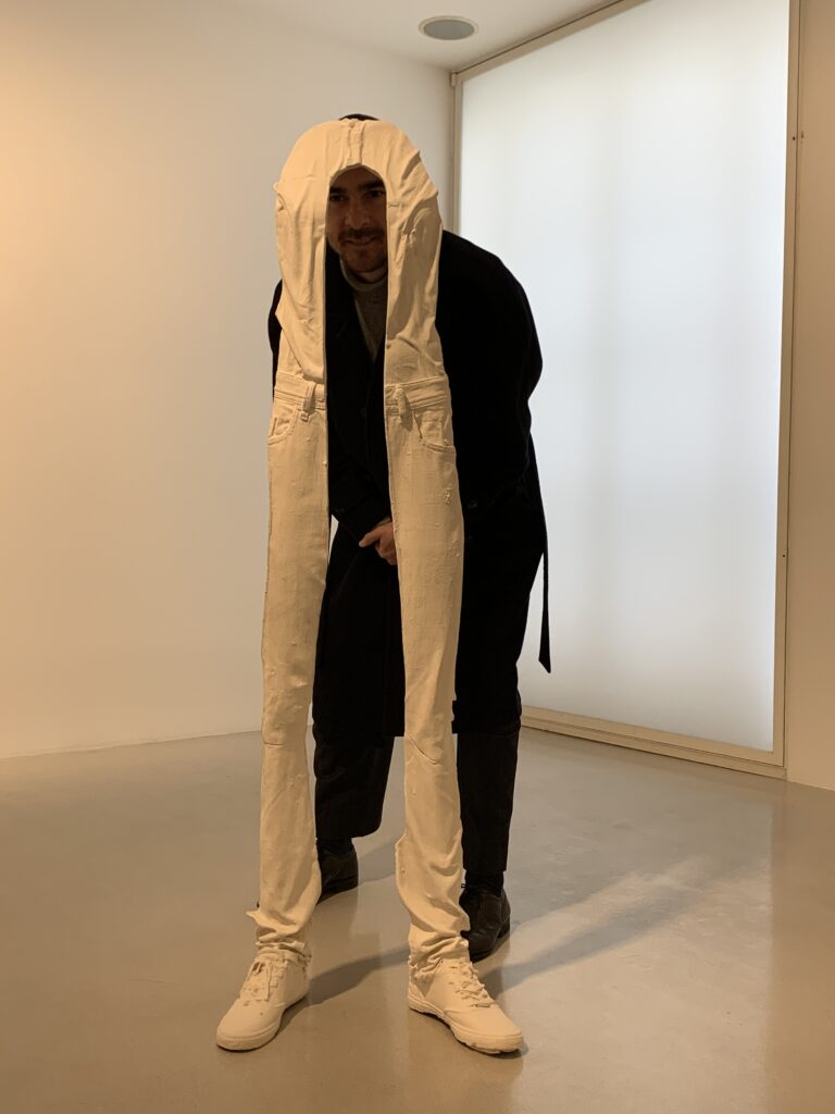 Photo of a man standing behind an abstract artwork of sneakers and elongated legs