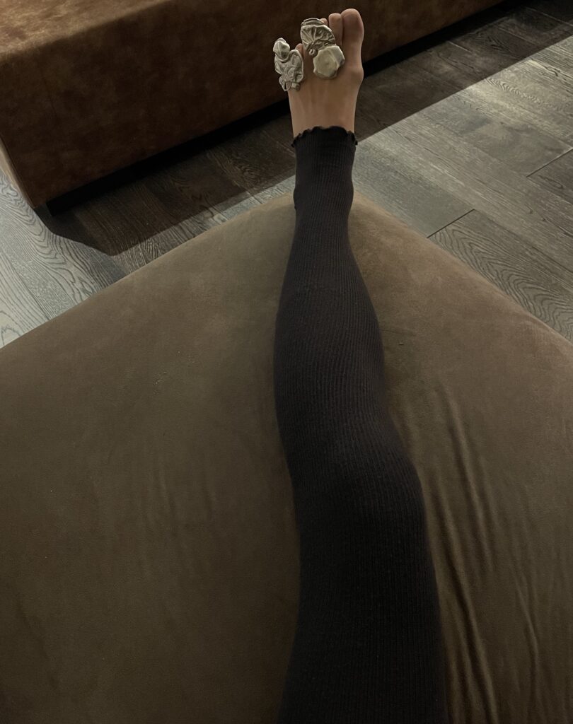Photo of extravagant silver toe rings being worn by a leg on the sofa