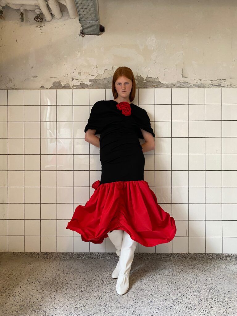 Image of a black and red skirt look with white boots against a tiled background